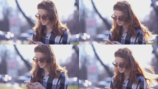 快乐微笑的女人戴着太阳镜和衬衫在她的智能手机上写信息高清在线视频素材下载