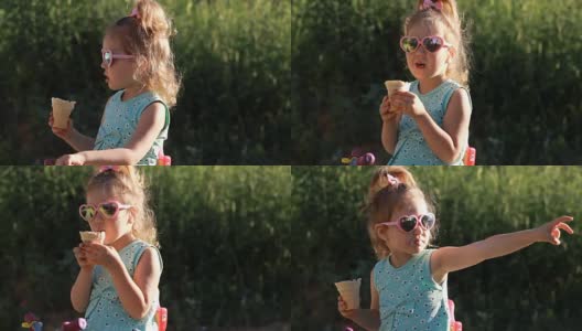 在一个阳光明媚的夏日，一个小女孩戴着太阳镜吃冰淇淋。高清在线视频素材下载