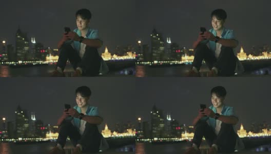 年轻的亚洲男人在晚上用手机高清在线视频素材下载
