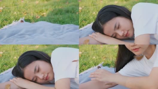 缓慢的动作年轻的亚洲女人睡觉，而躺在地面公园在春天，夏天，特写亚洲女孩午睡和躺在花园户外休息的背景，女性青少年休息，放松，幸福健康的生活方式高清在线视频素材下载