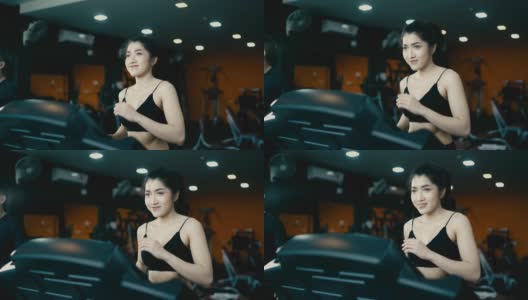 一位迷人的亚洲女子穿着黑色连衣裙在健身房里的跑步机上锻炼。高清在线视频素材下载