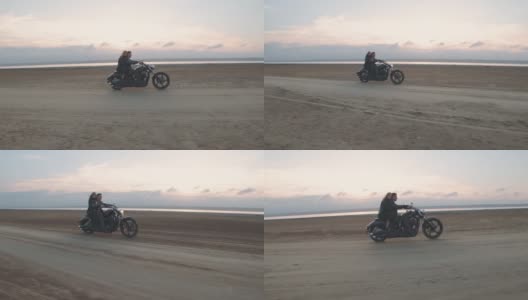 一个男人和一个女孩骑着摩托车在沙漠里。一对夫妇骑着老式摩托车，在一个干燥的盐湖上享受夕阳的美好时光。慢动作镜头高清在线视频素材下载