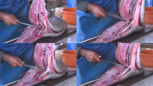 在传统的鱼市上，渔民们用剑把新鲜的金枪鱼切下来高清在线视频素材下载