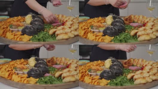 戴着防护手套的女厨师正在把意大利腊肠片摆放在小吃盘子里高清在线视频素材下载