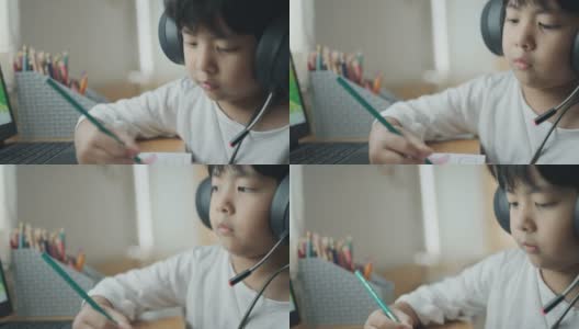 一个戴着耳机在家学习的男孩高清在线视频素材下载