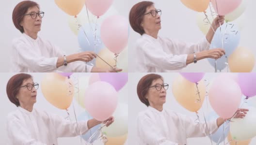 亚洲活跃的老年妇女用彩色气球庆祝生日高清在线视频素材下载