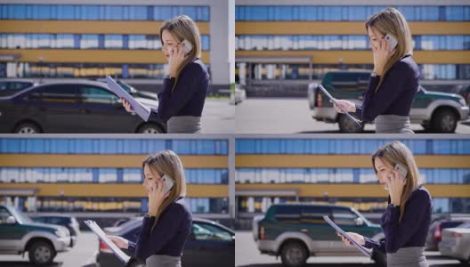 一位忙碌的商务女士拿着重要的合同，一边讲着手机，一边走过停着很多车的停车场高清在线视频素材下载
