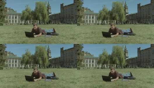 聪明的男学生在校园草坪上用笔记本电脑工作高清在线视频素材下载