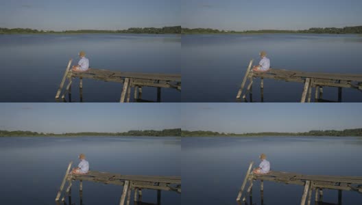 男孩坐在码头上，在湖里钓鱼，想着一些事情高清在线视频素材下载