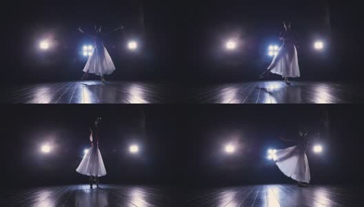 一个穿着飘逸长裙的单身芭蕾舞女演员在黑暗中表演。4 k。高清在线视频素材下载