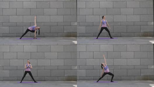 在灰色的城市背景下，一名女子在粉红色的垫子上练习瑜伽健身运动高清在线视频素材下载