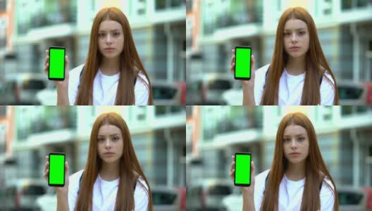 红发女孩展示绿色屏幕的智能手机，免费导航应用高清在线视频素材下载