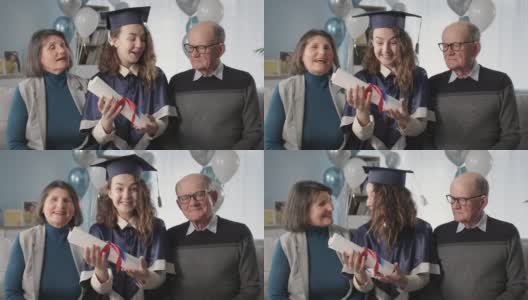 肖像幸福的家庭和研究生的女儿，戴着学位帽，穿着学位服，手里拿着文凭，在学年结束时，在远程教育高清在线视频素材下载