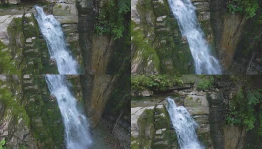 在夏季热带雨林中，美丽的瀑布在山河上，白色的泡沫水从岩石悬崖上落下高清在线视频素材下载