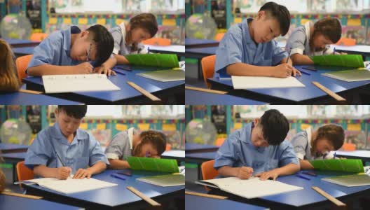 亚洲男孩坐在书桌上写他的教科书高清在线视频素材下载
