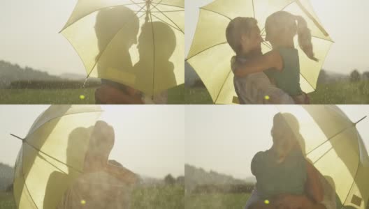 慢镜头:躲在黄色雨伞后面的情侣在雨中跳舞亲吻。高清在线视频素材下载
