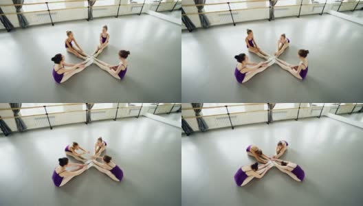 高角度的灵活的芭蕾舞者做头到膝盖弯曲坐在工作室的地板上伸展腿和背部。编排、灵活性和时间概念。高清在线视频素材下载