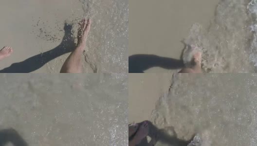 男人和女人脚的观点行走在沙滩上与水的冲击高清在线视频素材下载