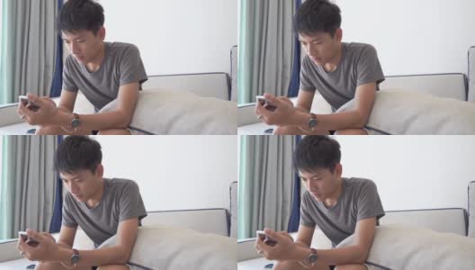 年轻的亚洲商人使用智能手机玩手机游戏，放松与网上购物在他的职业高清在线视频素材下载