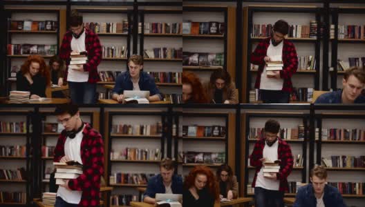 一个穿着格子衬衫戴着耳机的家伙带着一堆书走在旁边的慢动作镜头。其他同学坐着，在学院、大学图书馆里学习。前视图高清在线视频素材下载