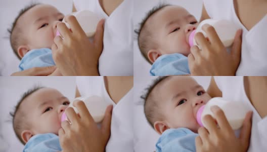 年轻的母亲在床上用奶瓶喂小婴儿。高清在线视频素材下载