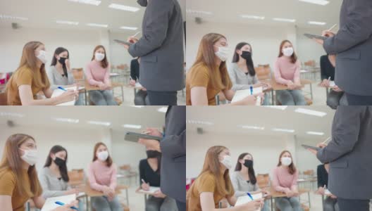 在大学教室里，一位老师用平板电脑给学生上课。学生戴口罩预防病毒新常态。高清在线视频素材下载