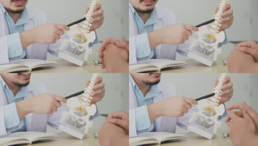 慢动作场景在物理治疗师的手指向人体骨骼在下背部，建议和咨询患者治疗在办公室为保健概念高清在线视频素材下载