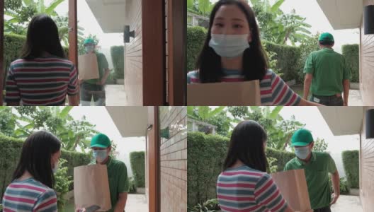 戴口罩的快递员将包裹交给一名亚洲妇女。高清在线视频素材下载