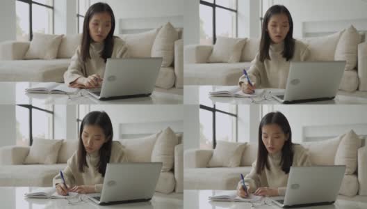一位年轻的亚洲女学生正在使用电脑和平板电脑。一位年轻的女商人正坐在办公桌前，在笔记本上记着笔记。教育和技术的概念高清在线视频素材下载