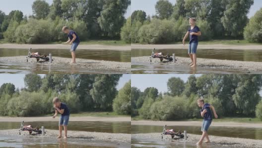 一个可爱的白人少年赤脚站在河边往水里扔石头。自然的休闲活动。缓慢的运动。高清在线视频素材下载