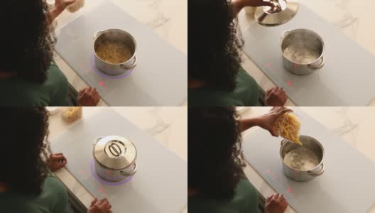 在智能感应炉灶上，一名妇女正在将意大利面放入沸水中煮高清在线视频素材下载