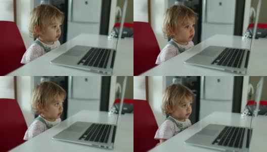 小男孩盯着笔记本电脑屏幕看媒体。婴儿看卡通片高清在线视频素材下载