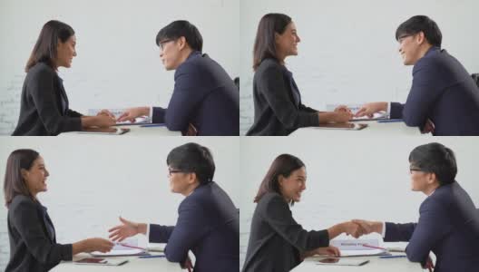 亚洲商人和女商人在办公室开会时讨论和握手谈生意。两个工人交谈和握手工作。团队合作的建议高清在线视频素材下载