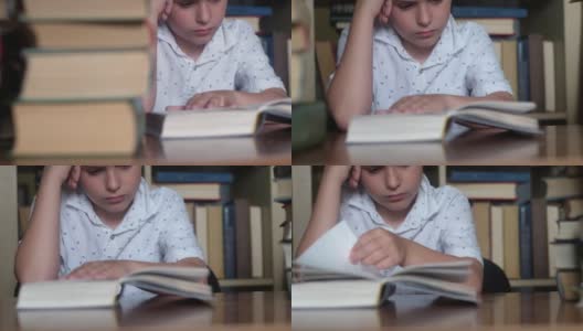 男孩坐在桌子旁的特写。读着书，小姐翻阅着书页。高清在线视频素材下载