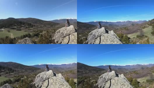 一位年轻女子独自坐在一块岩石上，观察法国的比利牛斯山脉高清在线视频素材下载