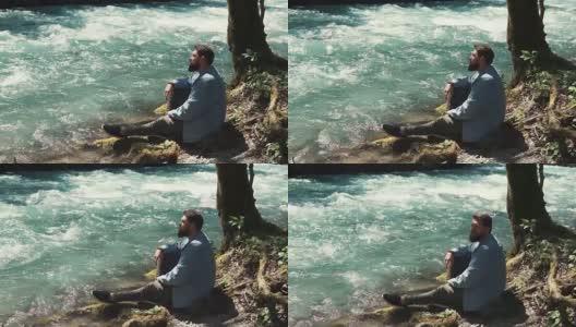 一个英俊的男人独自躺在森林的河岸上高清在线视频素材下载