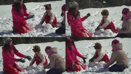 快乐的家庭在冬天的雪山森林里玩耍。妈妈和她的两个孩子扔雪球。做一个雪人。他们笑了。高清在线视频素材下载
