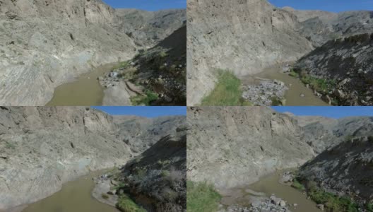 无人机在巨大的岩石峡谷中从一条孤独的河流中拉回高清在线视频素材下载