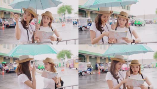 女人和朋友在看地图。亚洲女人享受曼谷Wat Pho的地标在曼谷市。在雨天，两名亚洲妇女撑着雨伞在泰国的主要寺庙中探险高清在线视频素材下载