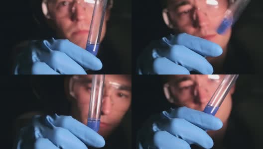 一位年轻的科学家兴奋地在试管中检查这种物质。化学实验室在黑暗中。高清在线视频素材下载