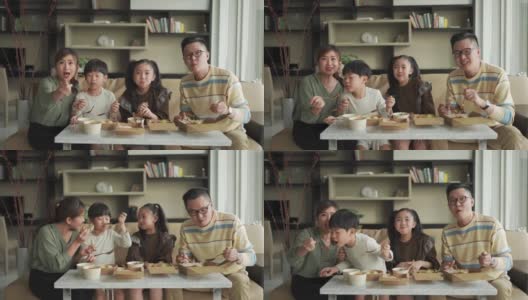 亚洲华人年轻家庭周末在客厅的电视前享受外卖食物高清在线视频素材下载