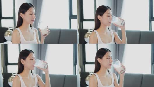 喝牛奶的亚洲年轻女子。早上下班之前。高清在线视频素材下载