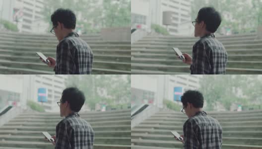 一名男子使用智能手机从现代办公大楼走出来高清在线视频素材下载