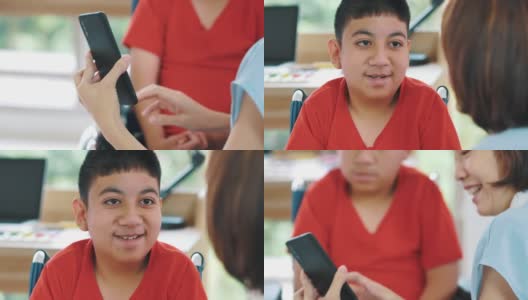女性看护者帮助残疾男孩(10-11岁)在家通过智能手机接受教育高清在线视频素材下载