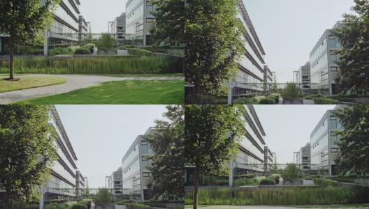 城市办公大楼的混凝土通道，左侧有一扇网门，右侧有绿树和灌木高清在线视频素材下载