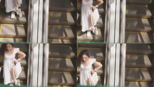 一名年轻女子提着五颜六色的购物袋在自动扶梯上逛商场高清在线视频素材下载