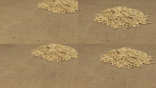 Zoom，走近的是一堆躺在粗麻布上的燕麦粒。特写镜头高清在线视频素材下载