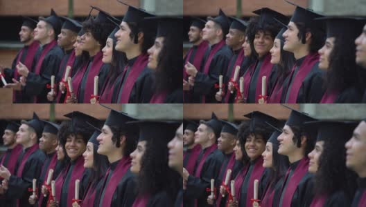 在毕业典礼上排队的毕业生们看向别处，而非洲裔年轻人看着镜头微笑高清在线视频素材下载