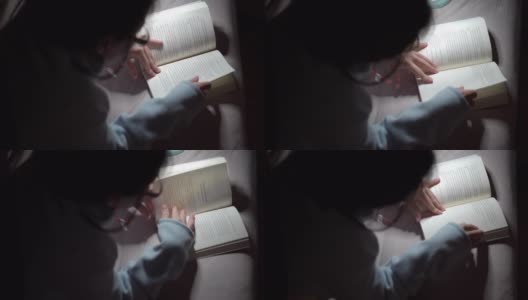 一个亚洲女人晚上在床上看书高清在线视频素材下载