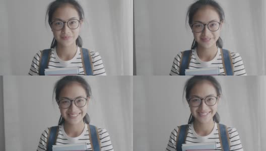 亚洲女人的肖像戴眼镜，快乐和微笑拿着书背包去学校，看着相机高清在线视频素材下载